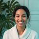 Close-up portrait of a smiling woman in her late 20s, looking content and relaxed against a soft forest green and aqua backgr