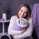 A smiling woman in her late 20s or early 30s, headshot, exuding warmth and trust against a soft lavender and charcoal backgro